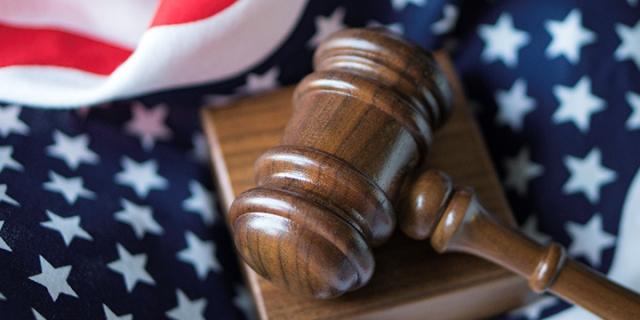 Wooden courtroom gavel sitting on American flag