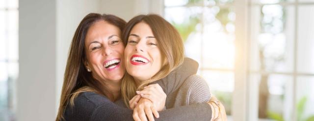older woman embracing younger woman from behind